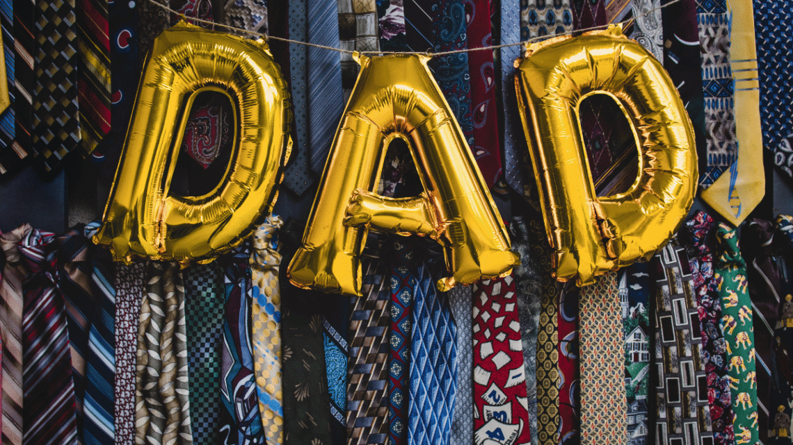 dad balloons and a tie themed banner behind them