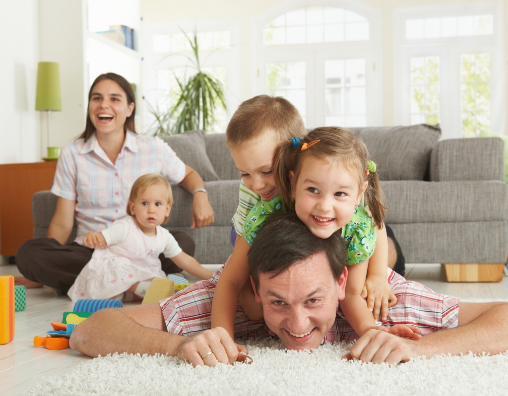 Happy family having fun on floor of in living room at home, laughing.