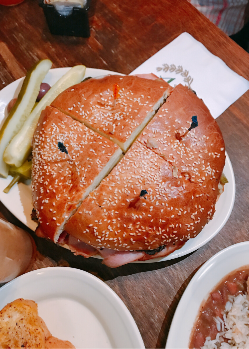 muffuletta sandwich at Napoleon house with seeded bun cut in four and pickles on the side