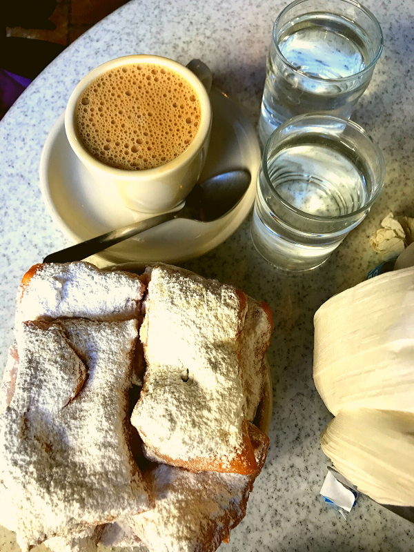 beignets at cafe du monde powdered sugar and coffee on table with water