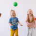 four young kids playing ball indoors and laughing