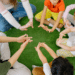 preschool kids in a circle sitting on a green carpet that looks like lawn stretching their hands