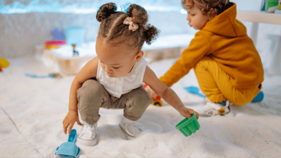 kids playing in a sandbox with what looks like little cars