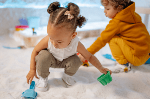 kids playing in a sandbox with what looks like little cars