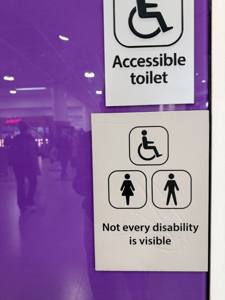 purple washroom door with a sign that says not every disability is visible