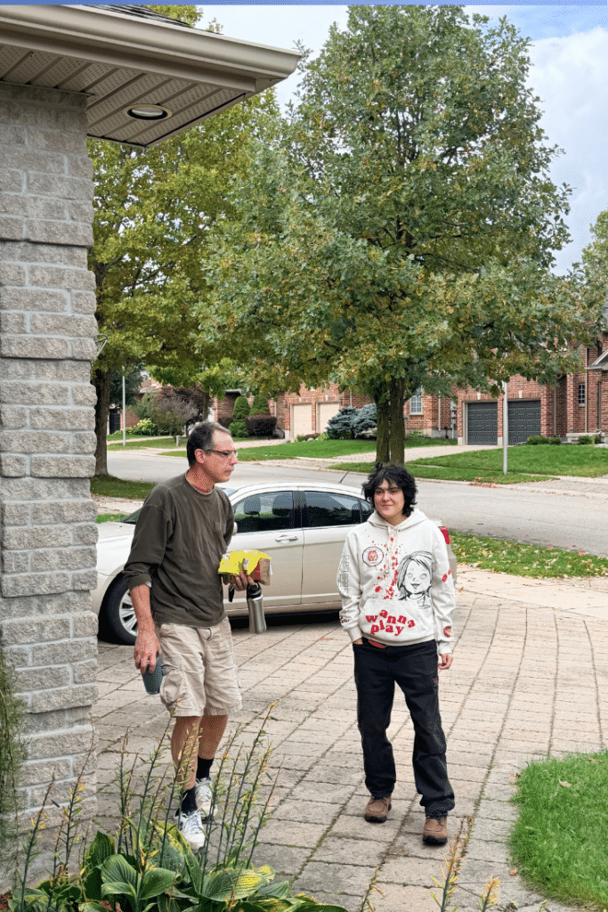 man and young adult child in driveway with car in the background and hostas in the foreground